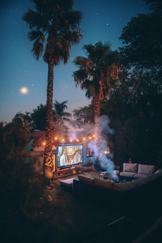 Outdoor projector and blow-up screen set up for a pool party movie night