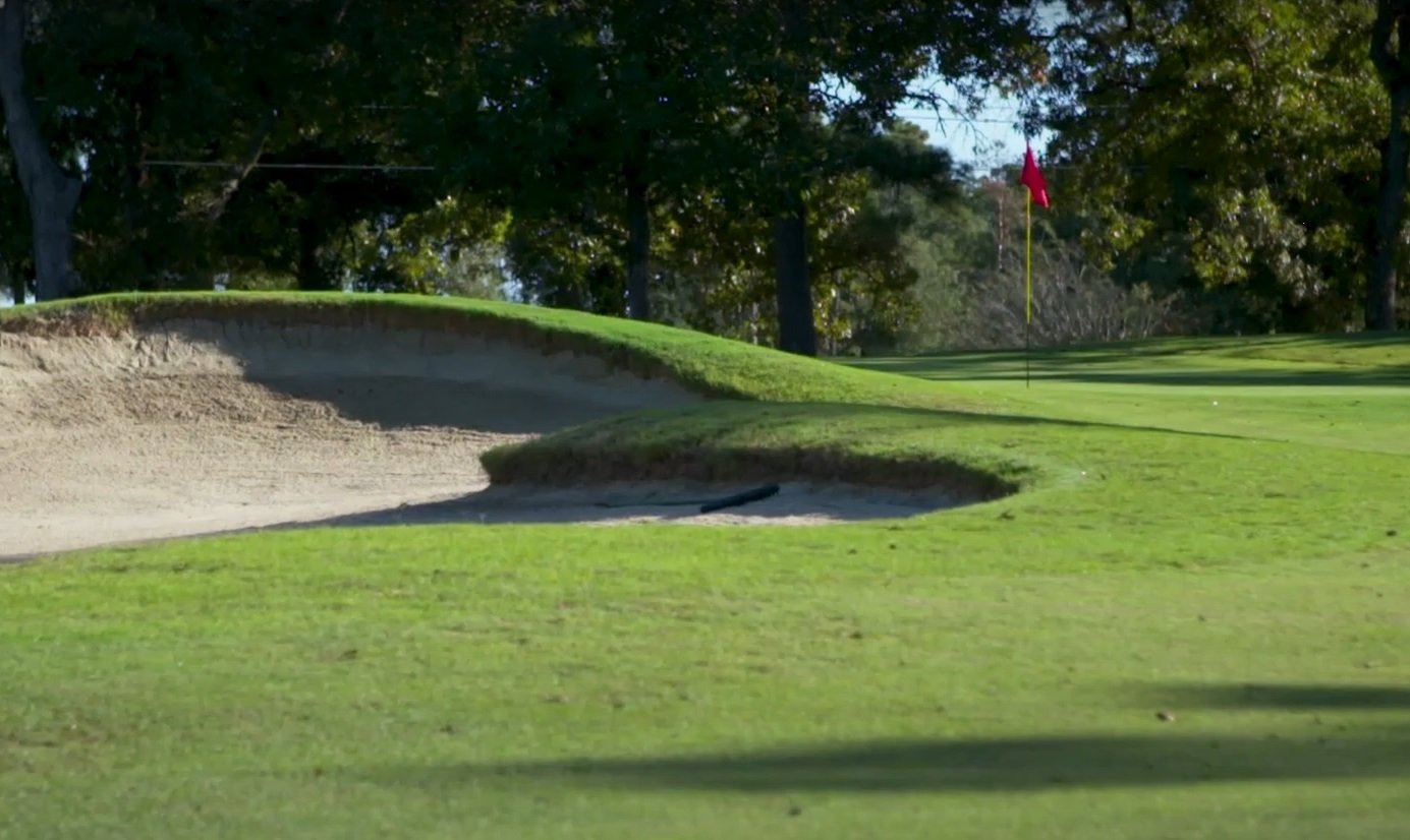 Sand bunker and red flag on a tree-lined course