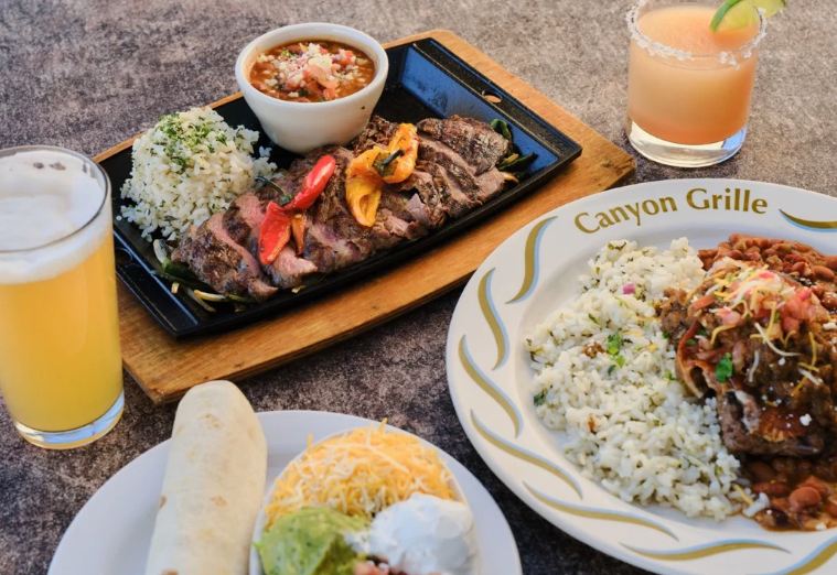 Several plates of food and beverages on a table.