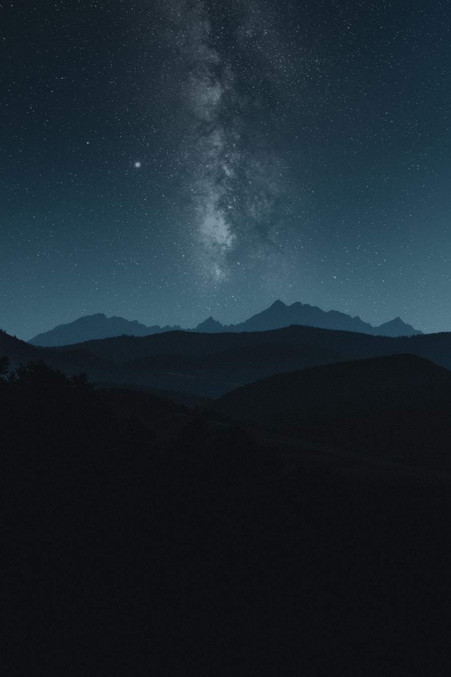 Starry night sky over silhouetted Rocky Mountain peaks