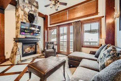 Living and dining area of Unit 8505 at One Ski Hill Place, with custom copper ceiling, marble floors, and a stone gas fireplace