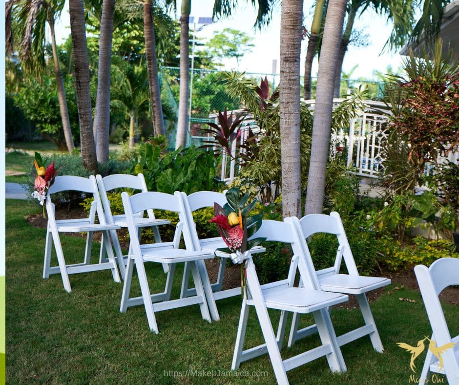 white garden chairs set up for a garden wedding at a Jamaica wedding venue