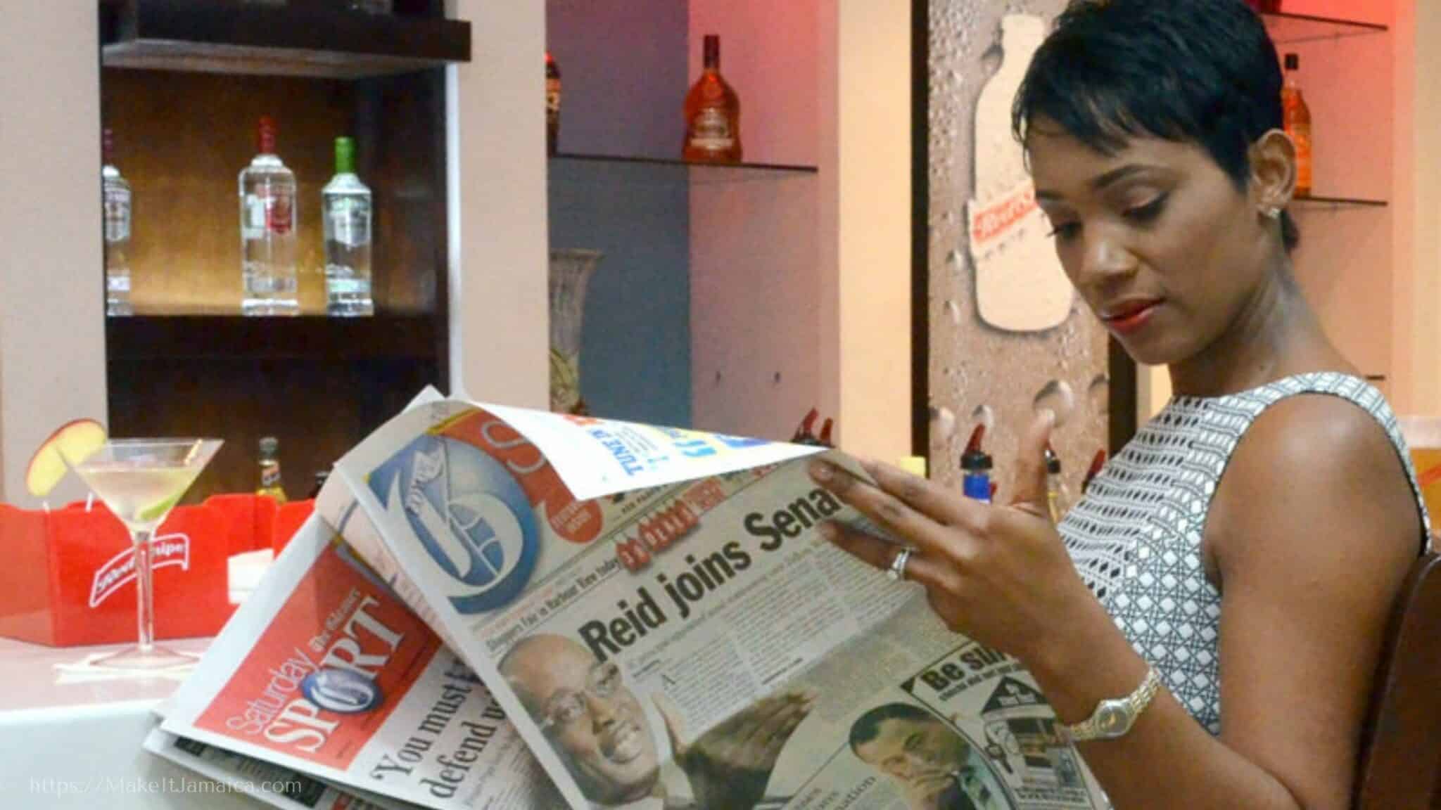 woman reading the newspaper in the Club Mobay in Jamaica departure lounge