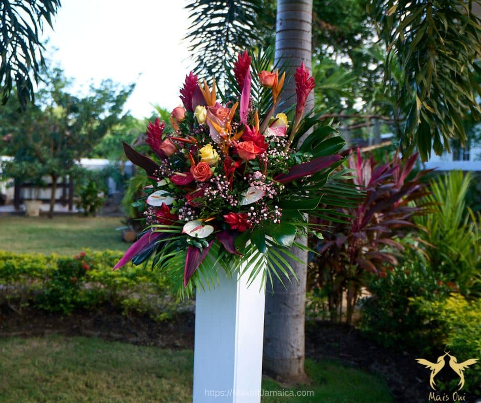White pedestal with tropical floral arrangement at a garden wedding venue in Jamaica