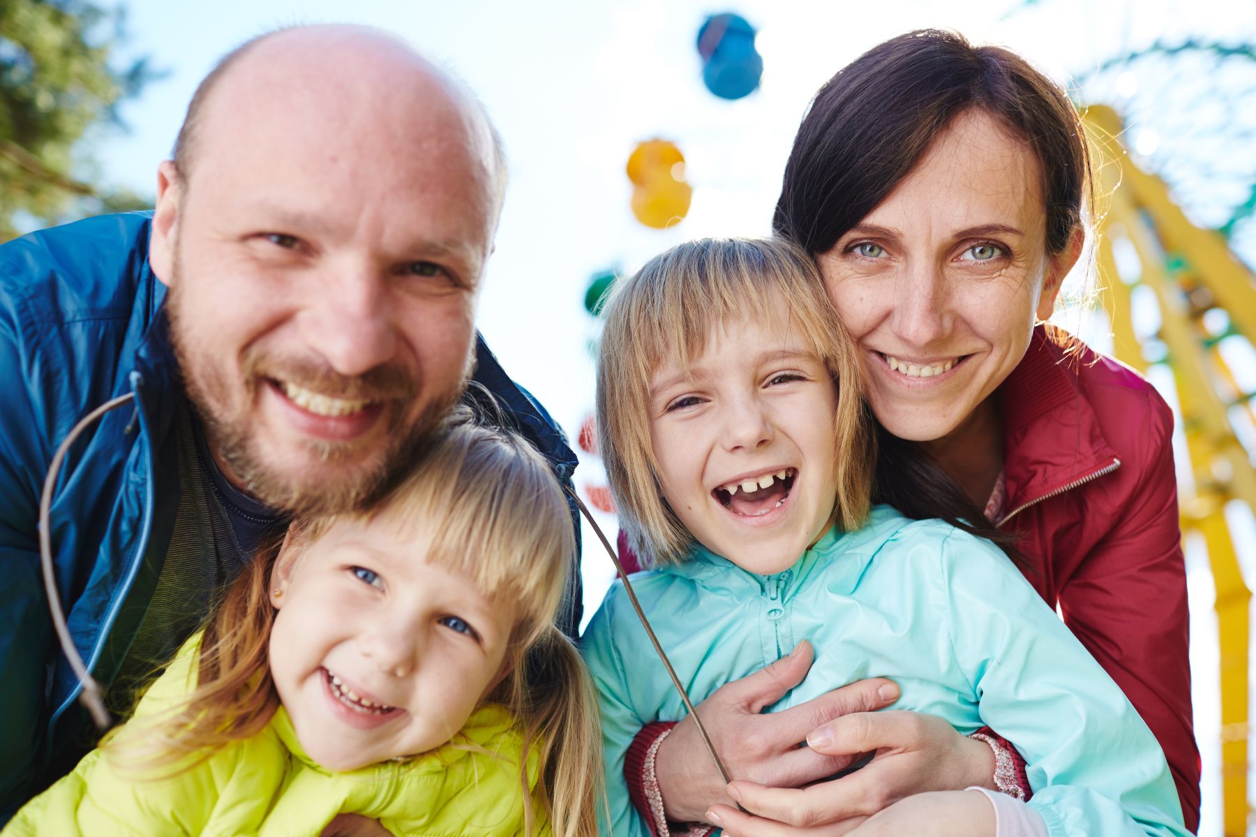 family smiles in front of Ferris wheel