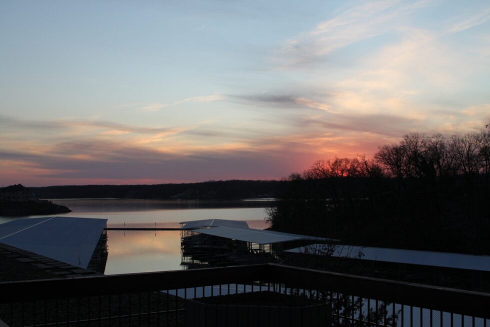 Soft pink and blue sunset over Lake of the Ozarks in the off-season, viewed from a hillside above a covered boat dock