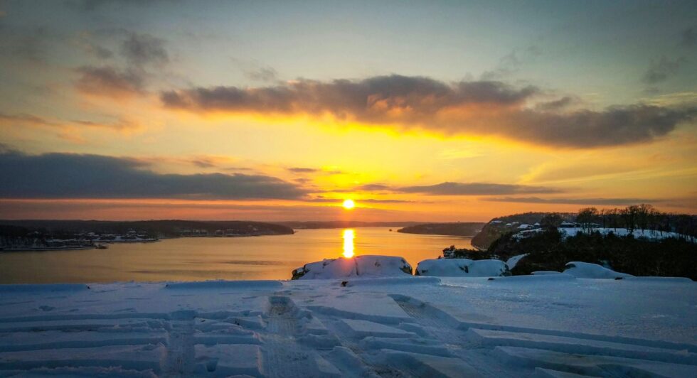 Golden winter sunset over Lake of the Ozarks with snow-covered bluffs in the foreground and the lake stretching toward the horizon