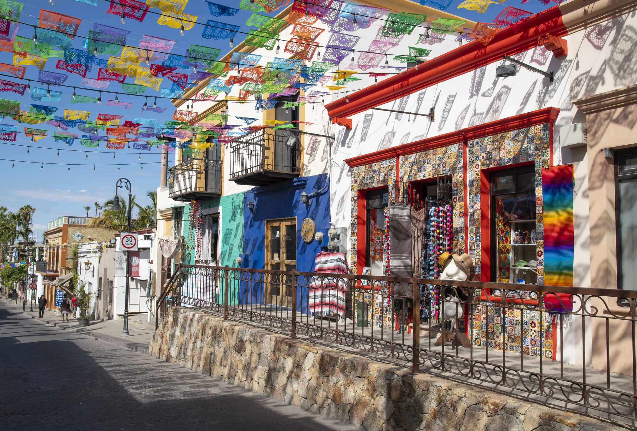 Colorida calle mexicana con banderines de papel picado colgados en lo alto y tiendas de artesanías a lo largo de la acera