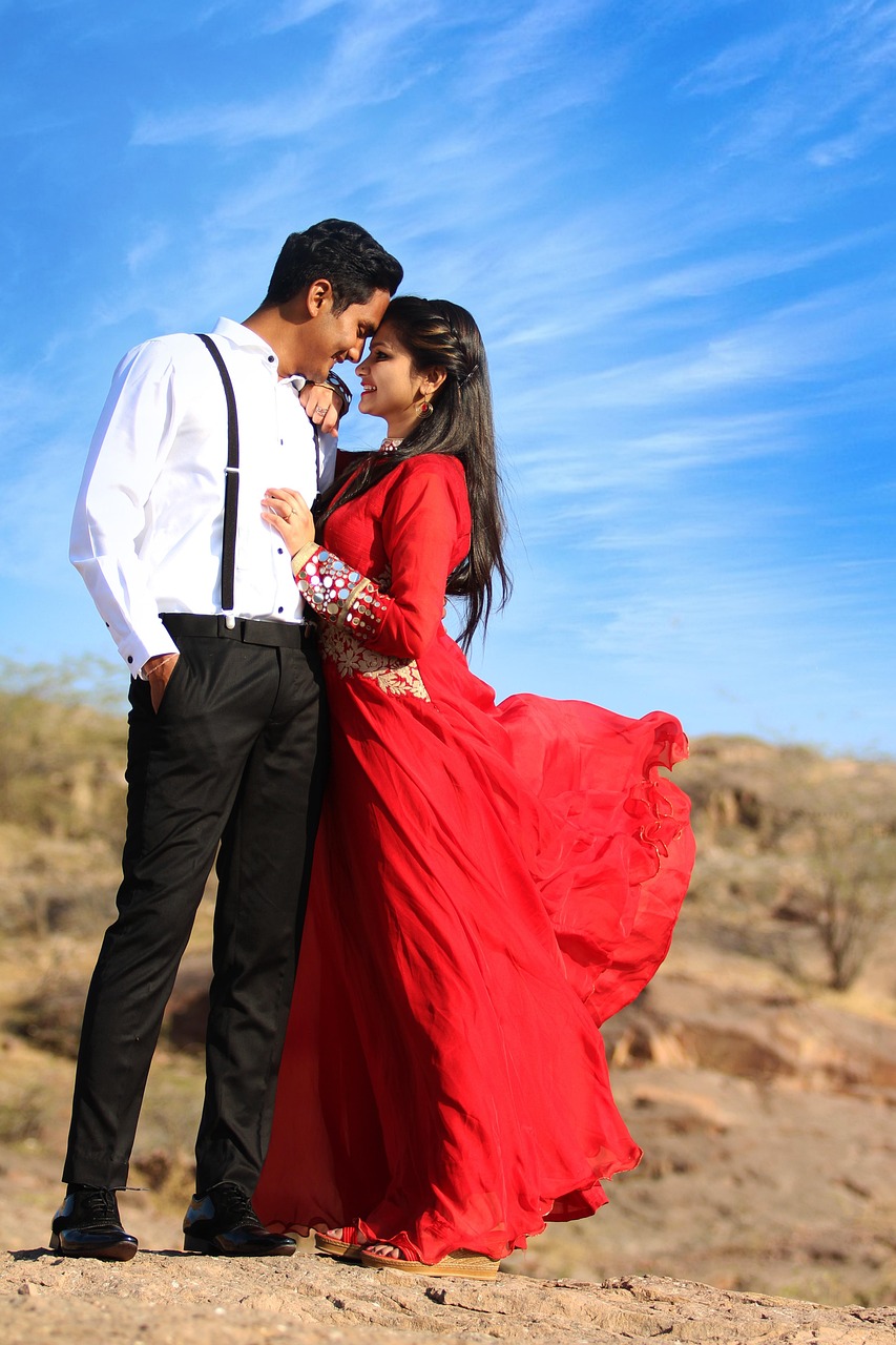 Pareja vestida de gala abrazándose en una ladera rocosa y desértica bajo un cielo azul