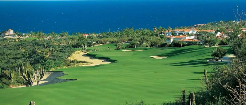Vista aérea del campo de golf Palmilla, con cactus, búnkeres de arena, palmeras y el Sea of Cortez al fondo