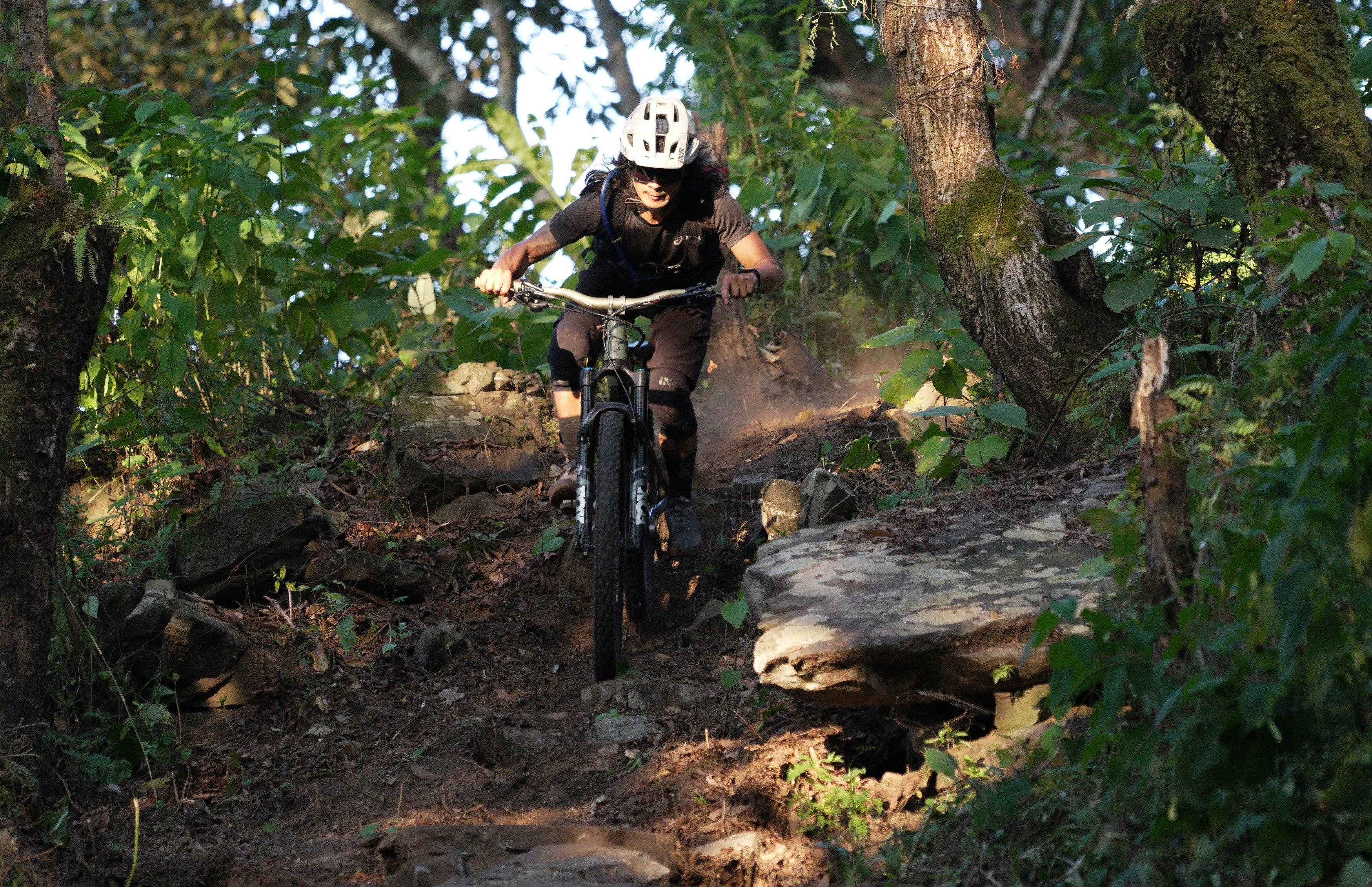Ciclista de montaña descendiendo a toda velocidad por un sendero rocoso entre matorrales secos