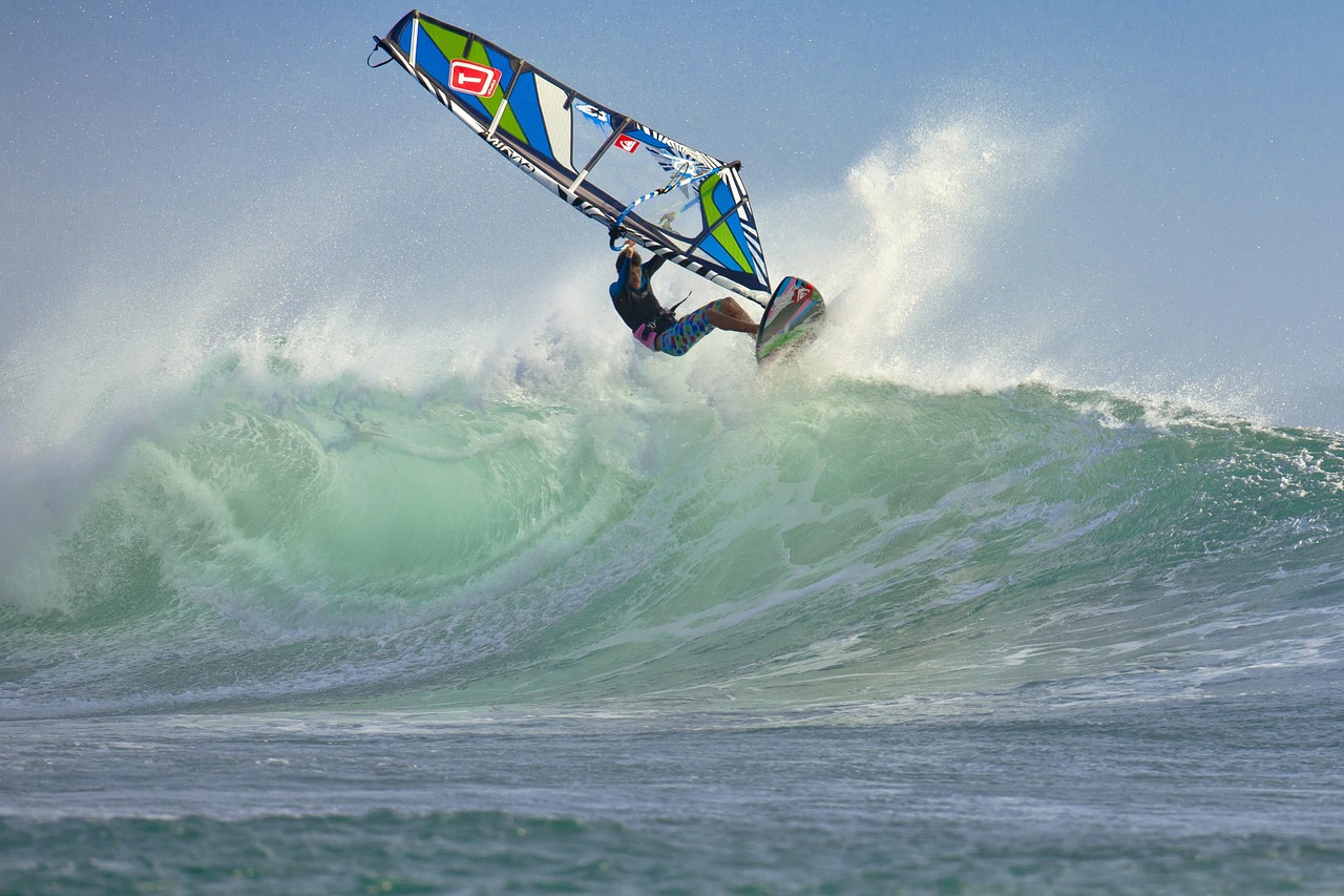 Practicante de windsurf saltando desde la cresta de una gran ola rompiente