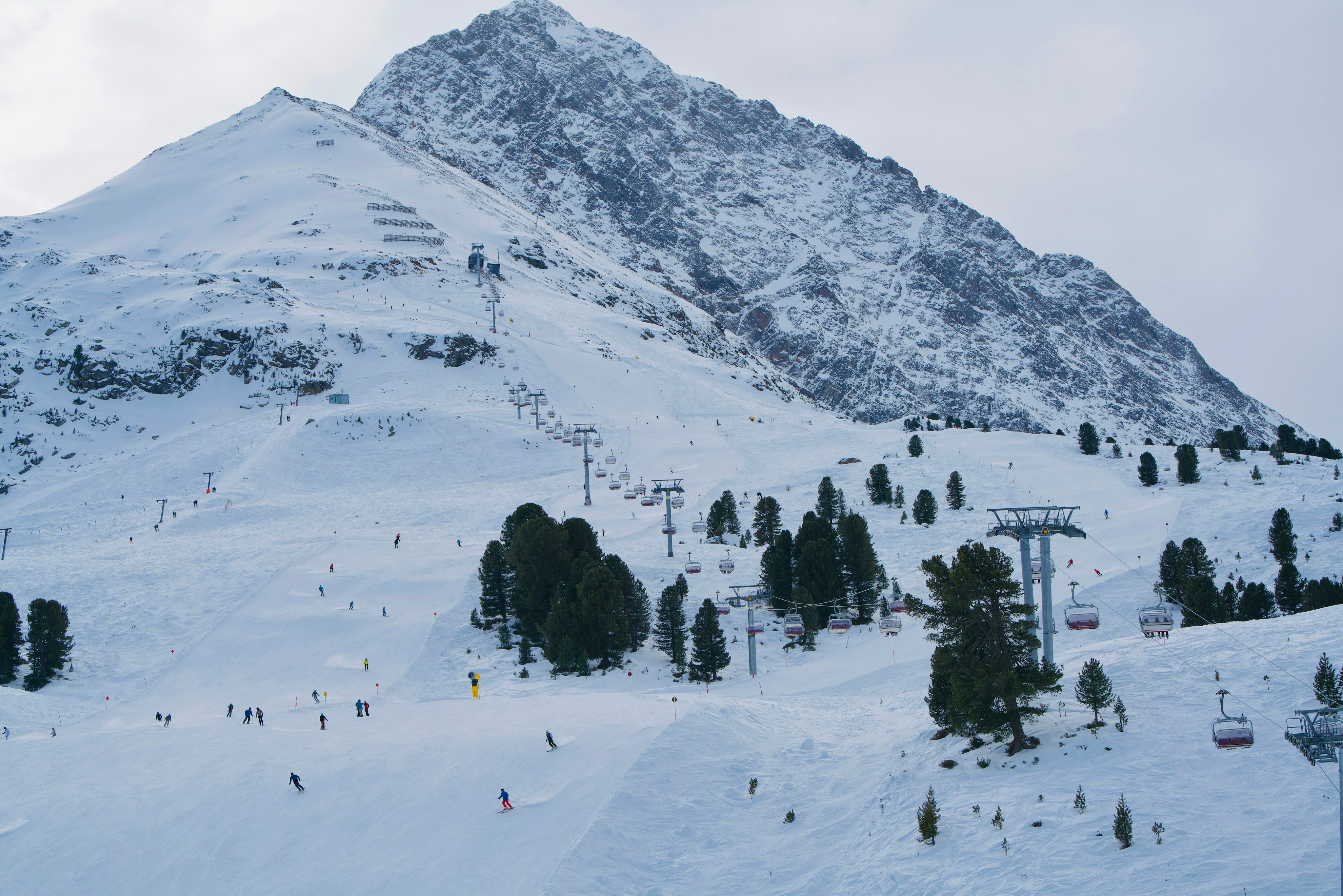 Wide ski resort slope with skiers and chairlifts on a snowy mountain