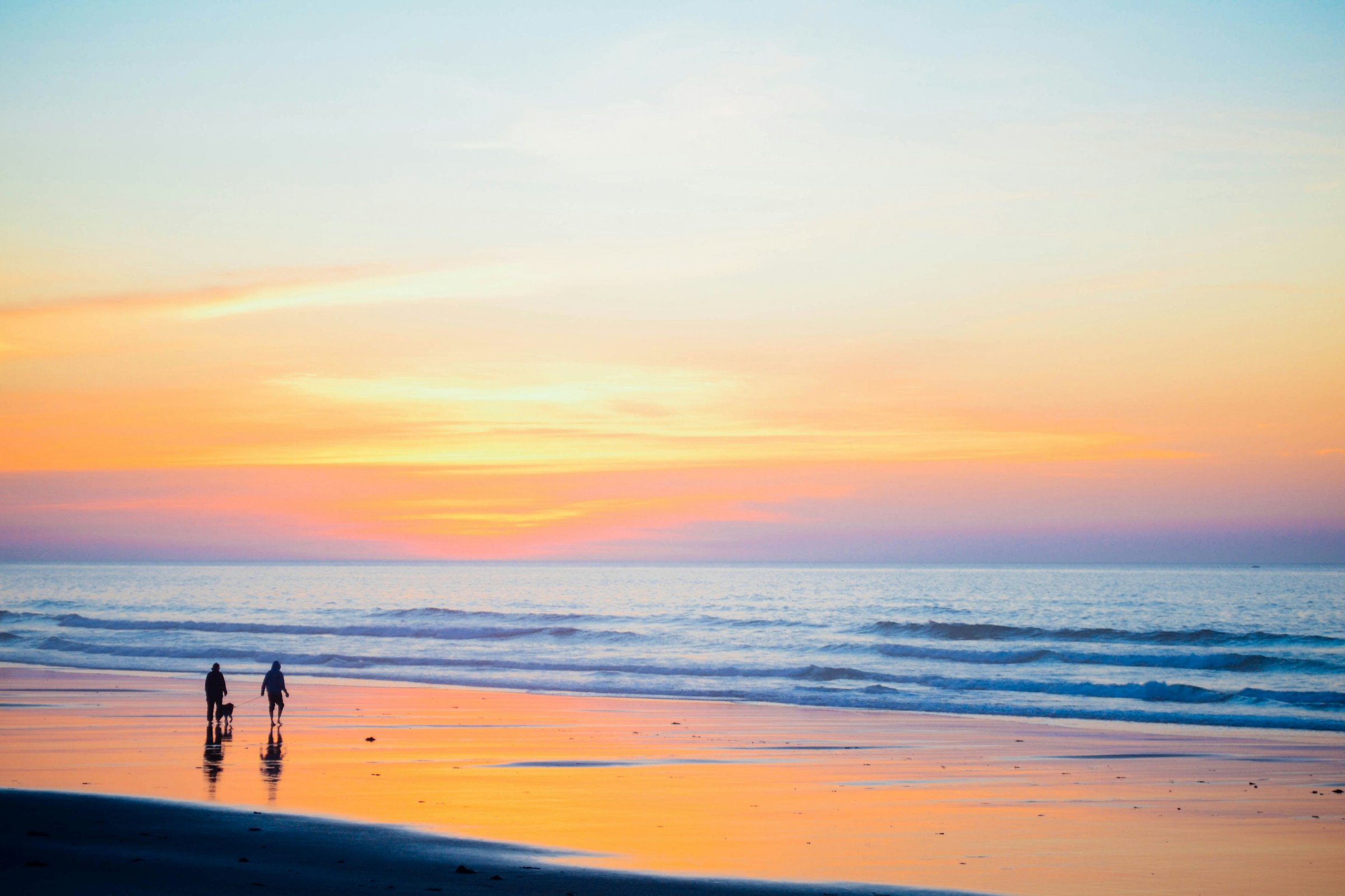 Sand and surf at Moody Beach in Wells, Maine on a clear summer morning with beachgoers walking the shoreline