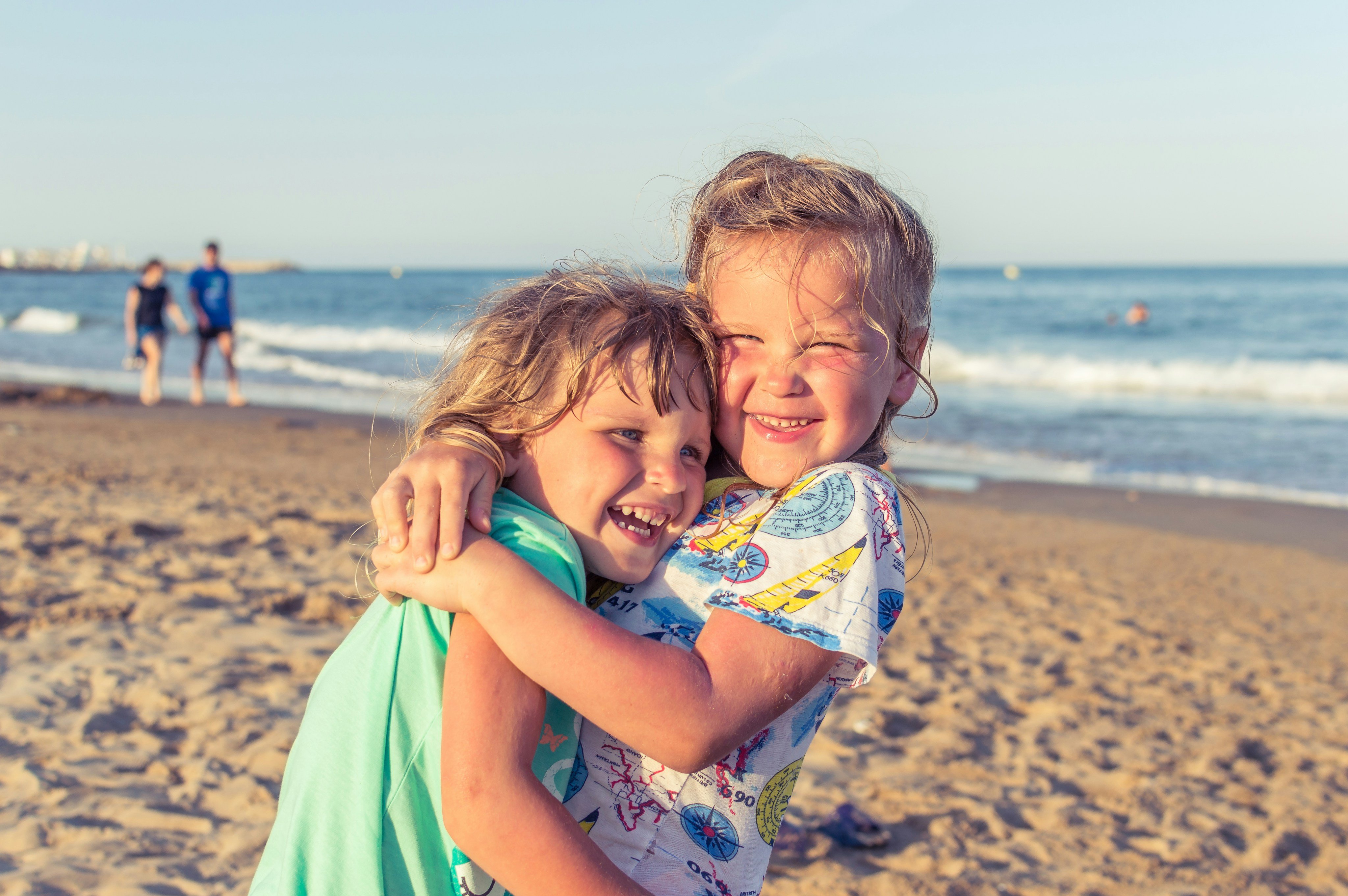 Two kids hugging and laughing on a sunny beach