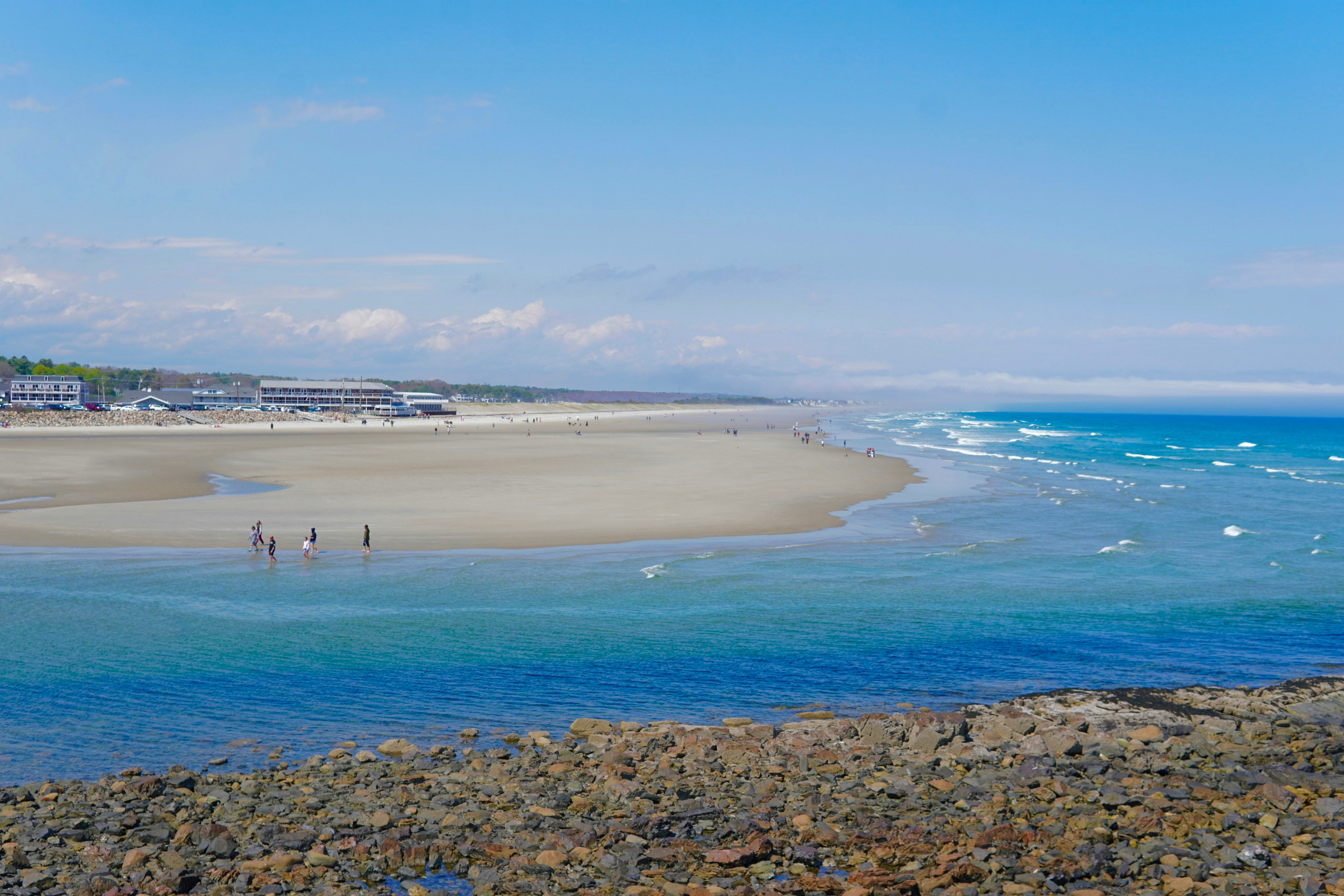 Maine beach with clear blue water and a distant coastal town