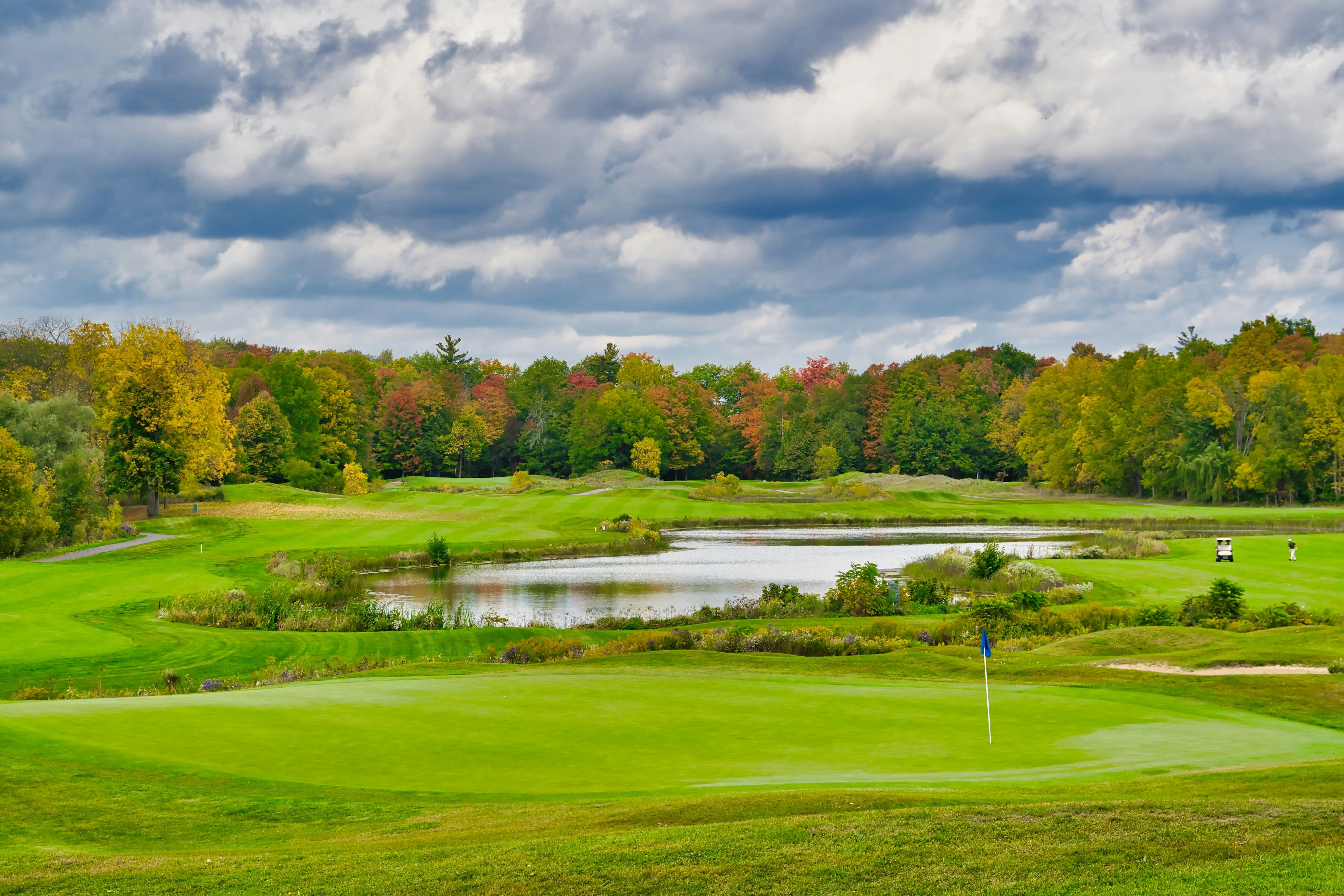 Golf course green with autumn trees and pond