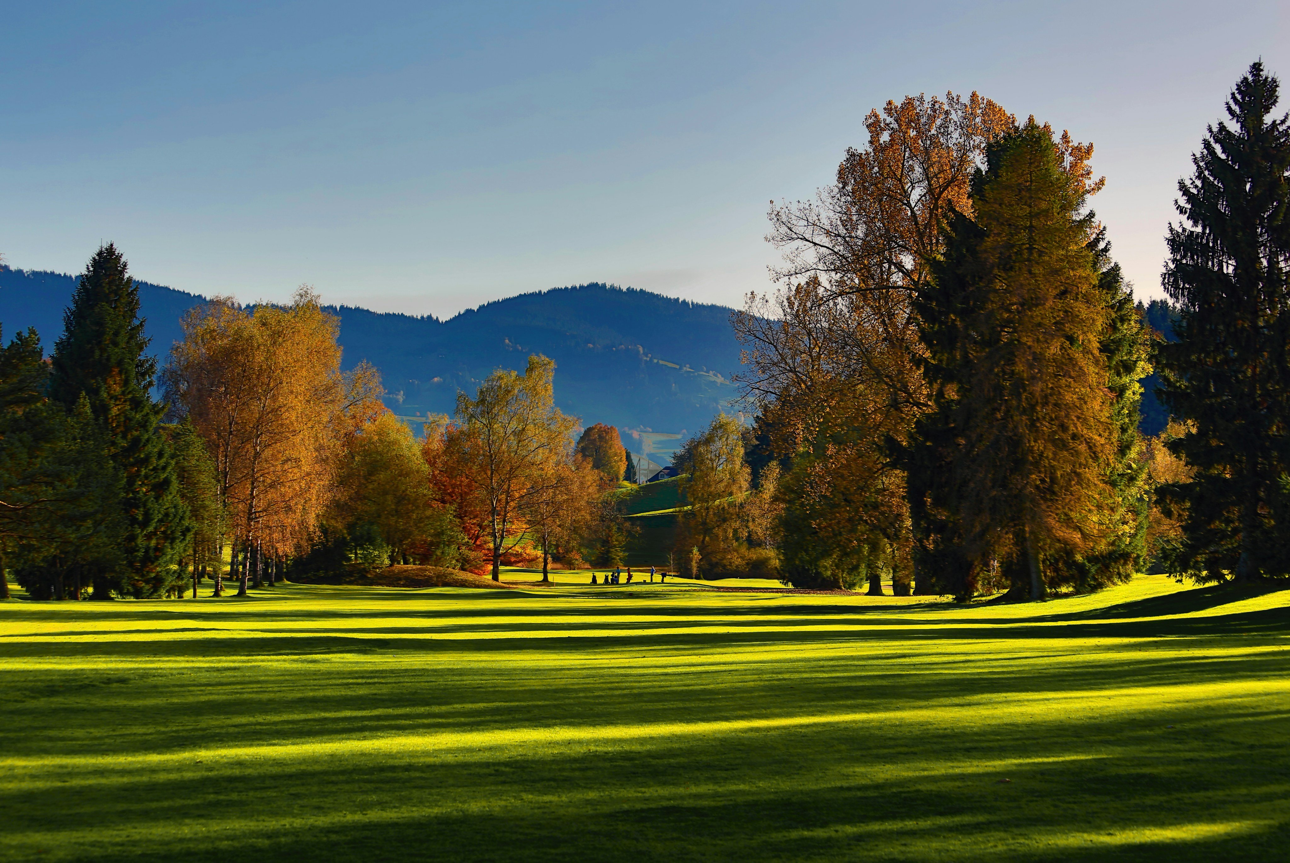 Golf course fairway with mountain backdrop in autumn
