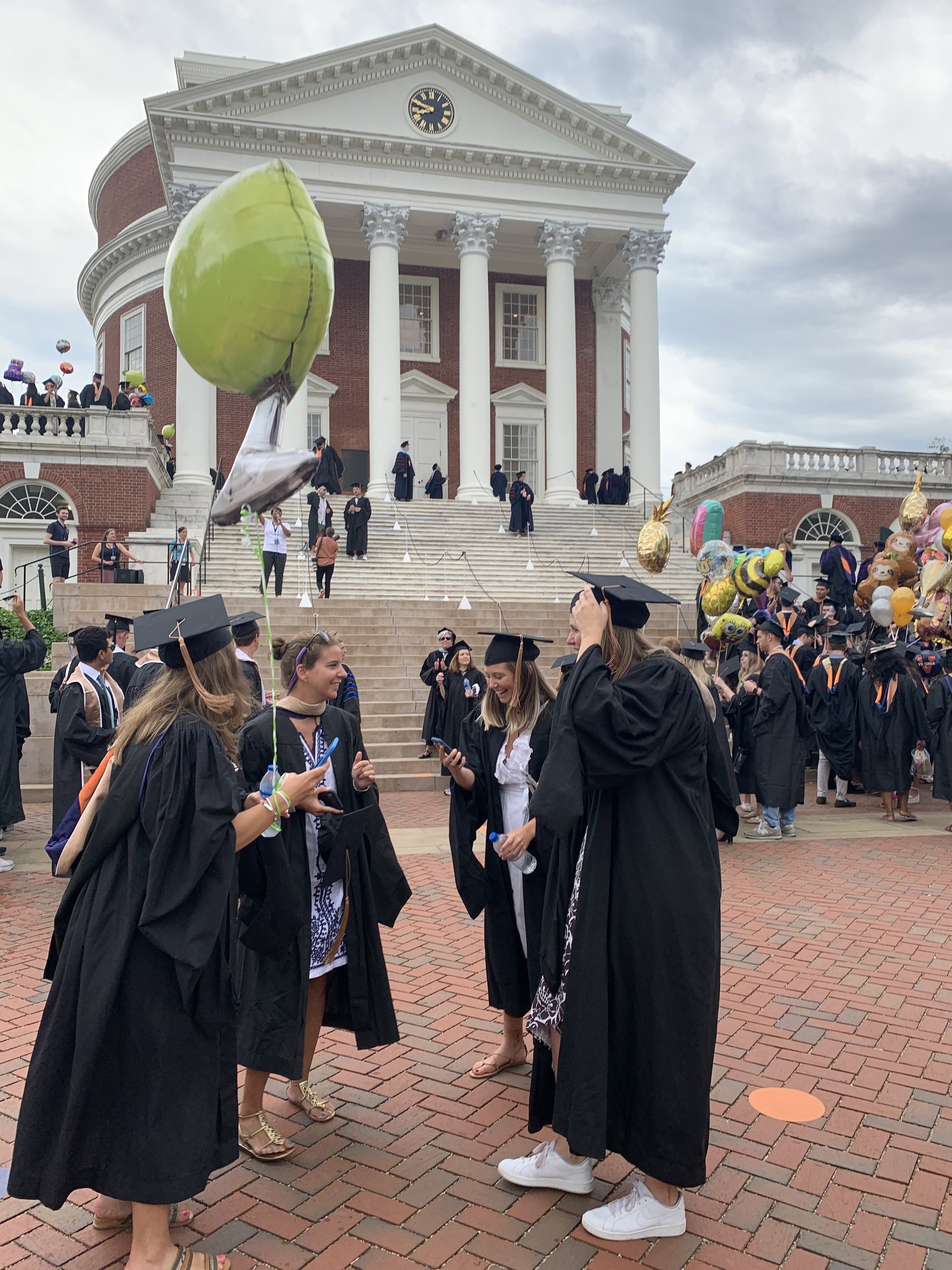 Four friends in graduation robes standing in front of the UVA Rotunda