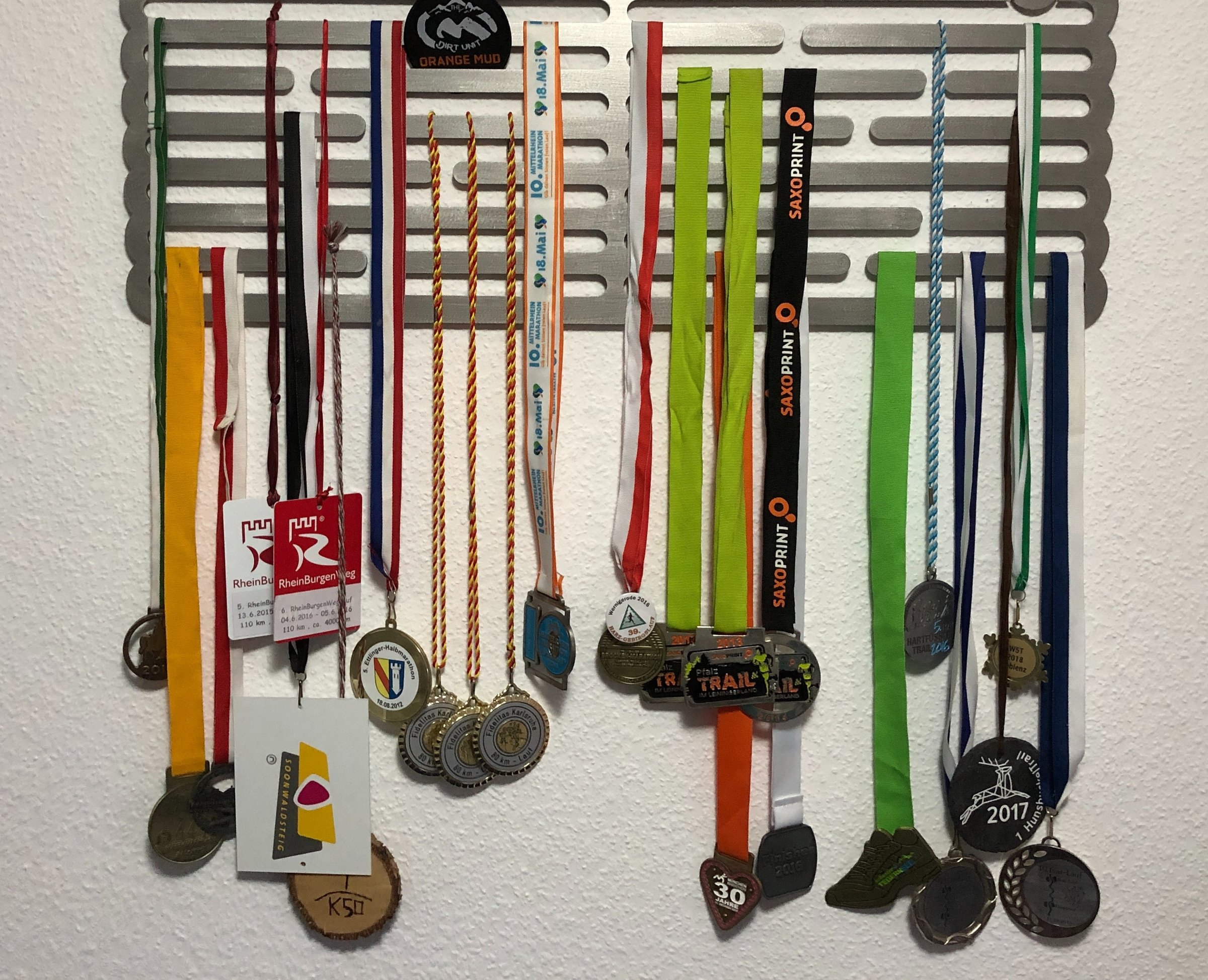 multiple, multi-color running medals hanging on wall