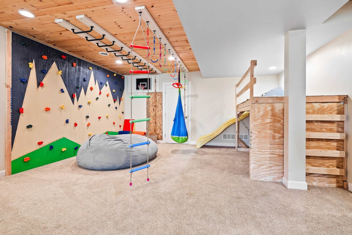 colorful basement playroom with jungle gym and climbing wall for kids in short term rental