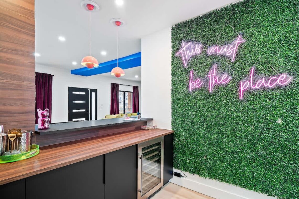 Modern open-concept kitchen and living area in a Great Lakes vacation rental, with a green accent wall and neon lighting