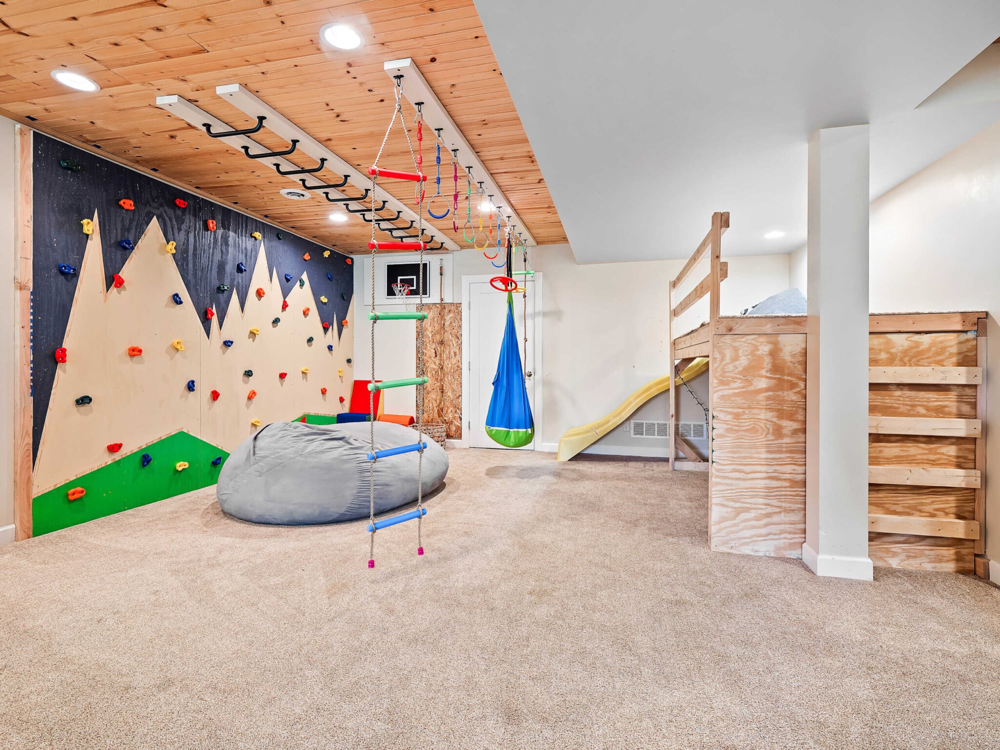 colorful basement playroom with jungle gym and climbing wall for kids in short term rental