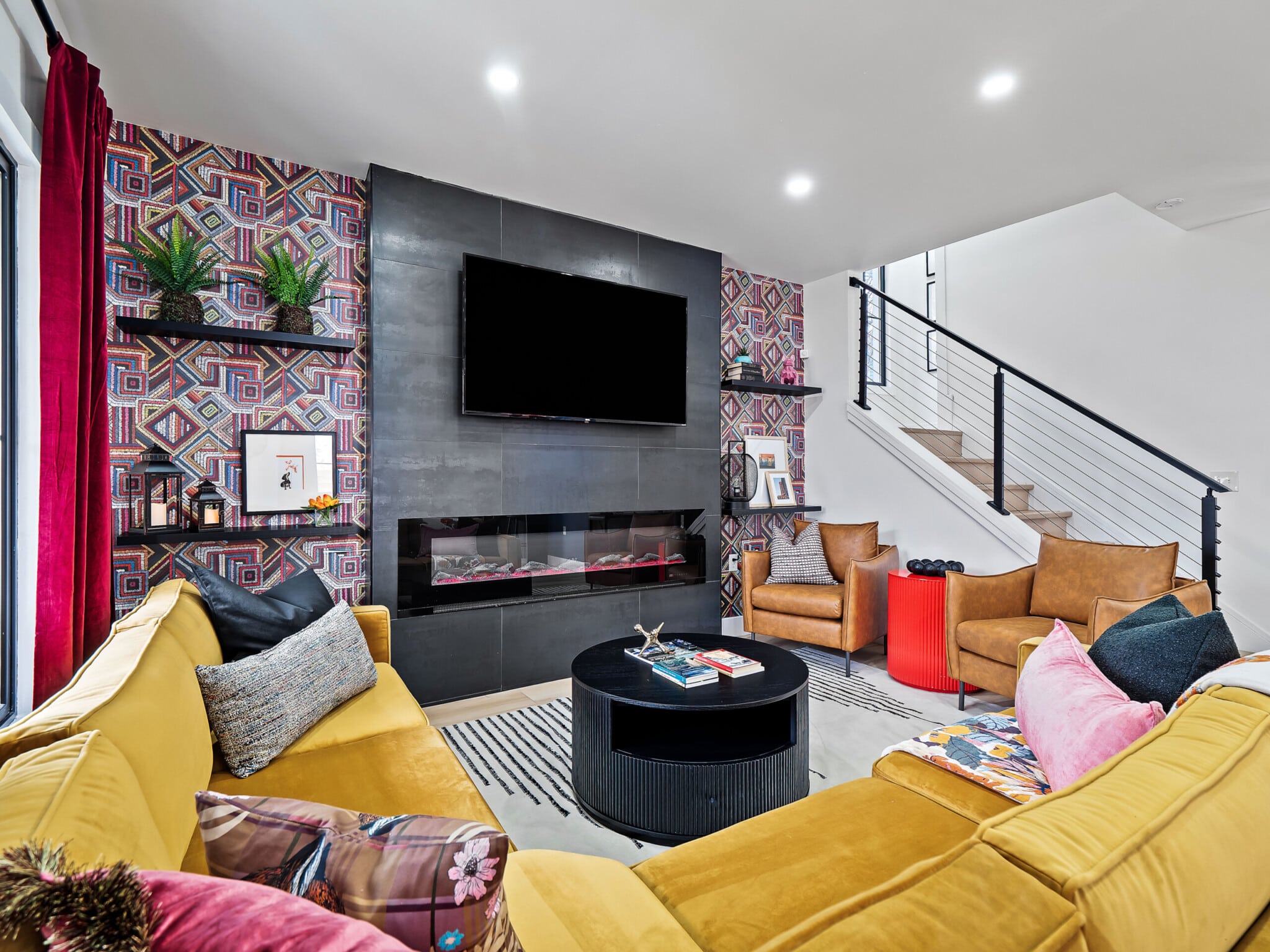 Modern short-term rental living room with accent wall design, fireplace, large flat-screen TV, and spacious seating area for guests