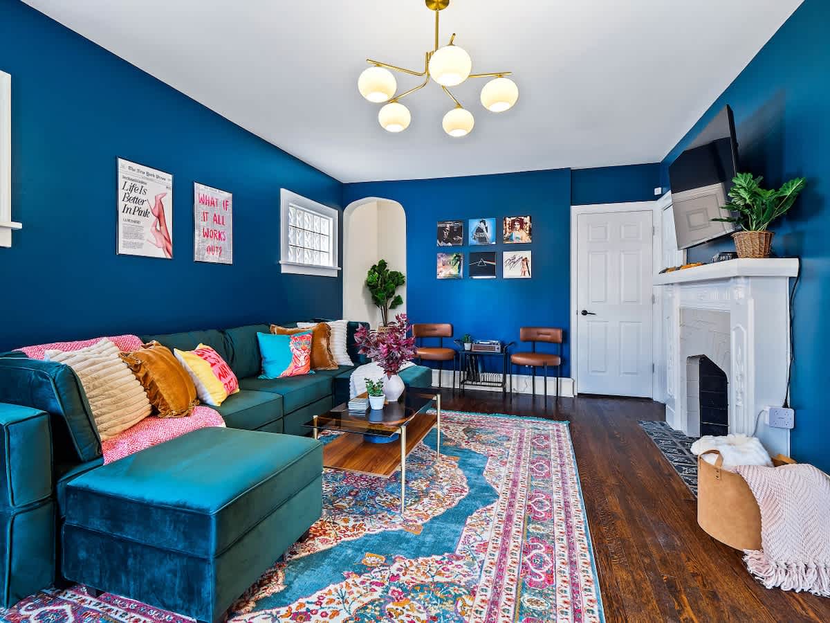 Modern vacation rental living room with colorful pillows, blue accent walls, and inviting seating for guests