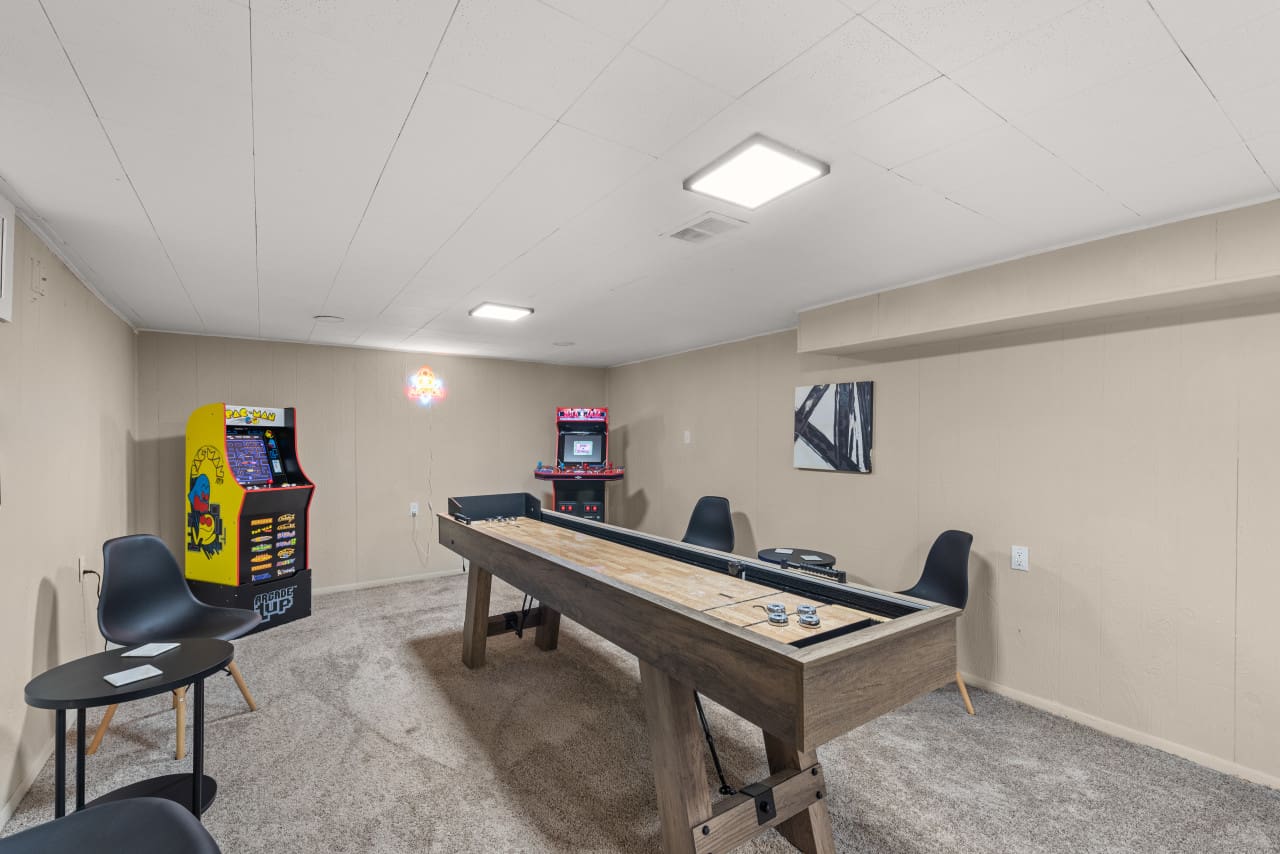 Game room in Northeast Ohio vacation rental with shuffleboard table and arcade games, perfect for guest entertainment