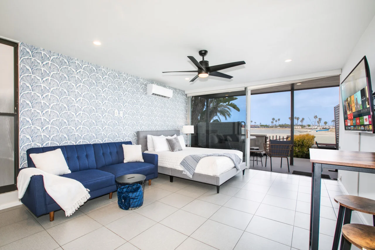 Modern San Diego beachfront bedroom with ocean view, blue sectional sofa, and queen bed ready for turnover coordination and