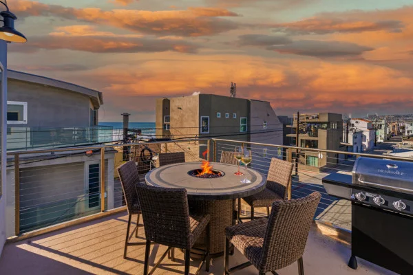 San Diego vacation rental rooftop patio with fire pit dining table and grill overlooking coastal city skyline at sunset