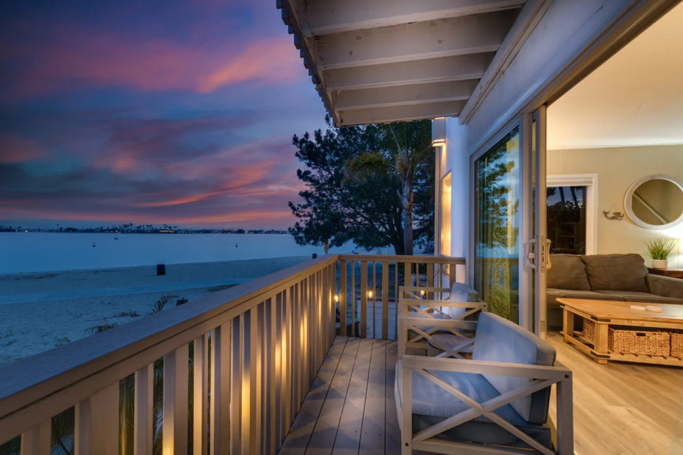 San Diego waterfront patio at twilight with covered deck, white railings, and lounge chairs overlooking calm bay water ideal