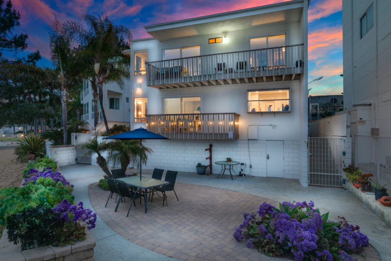 Modern beachfront home exterior with patio, purple flowers, and sunset views in San Diego coastal neighborhood