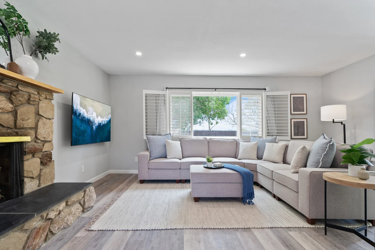 Modern living room with gray sectional, fireplace, and natural light in San Diego rental