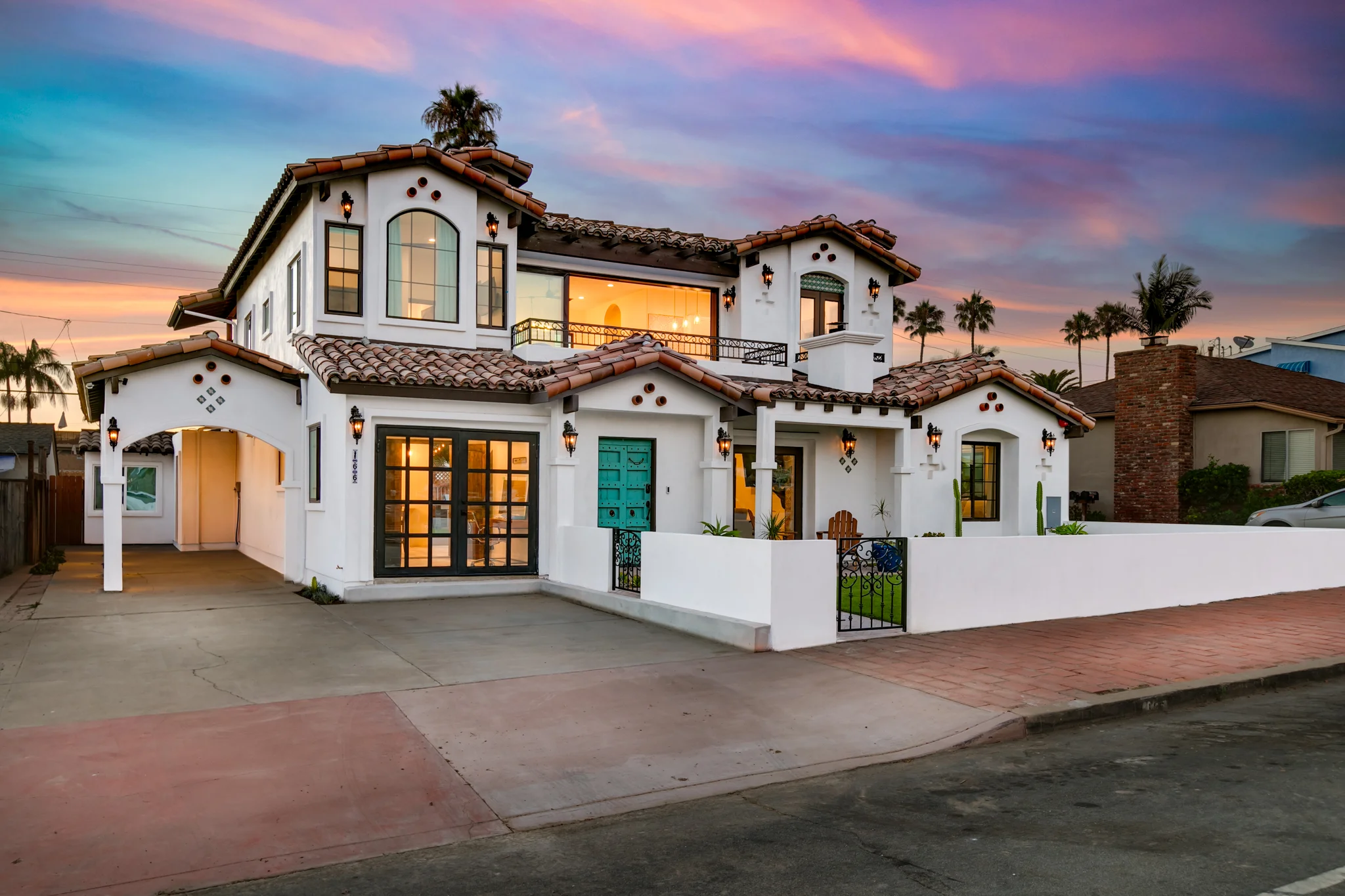Spanish-style San Diego vacation rental exterior with white stucco, terracotta roof, and sunset lighting
