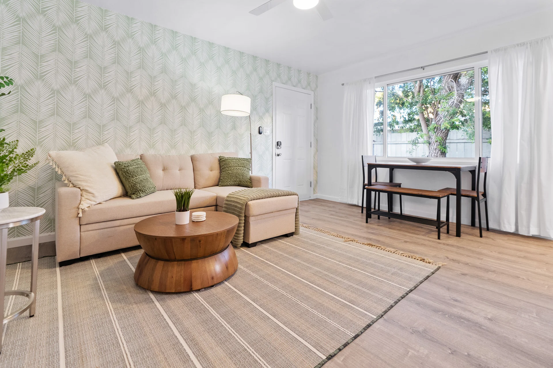 Modern living room with cream sectional sofa and green pillows showing the type of San Diego vacation rental space guests