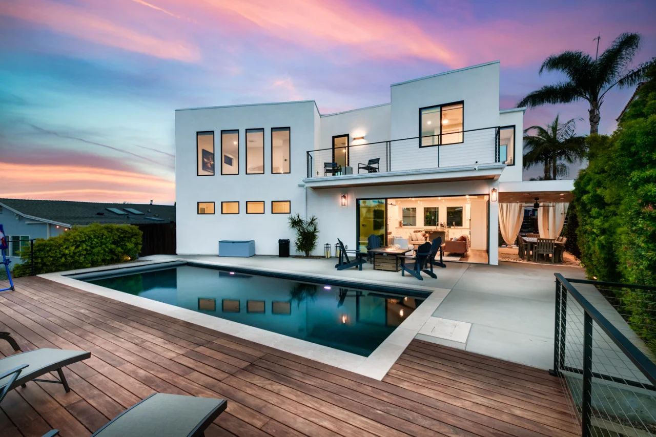 Modern white house exterior with illuminated pool and deck, luxury San Diego rental property