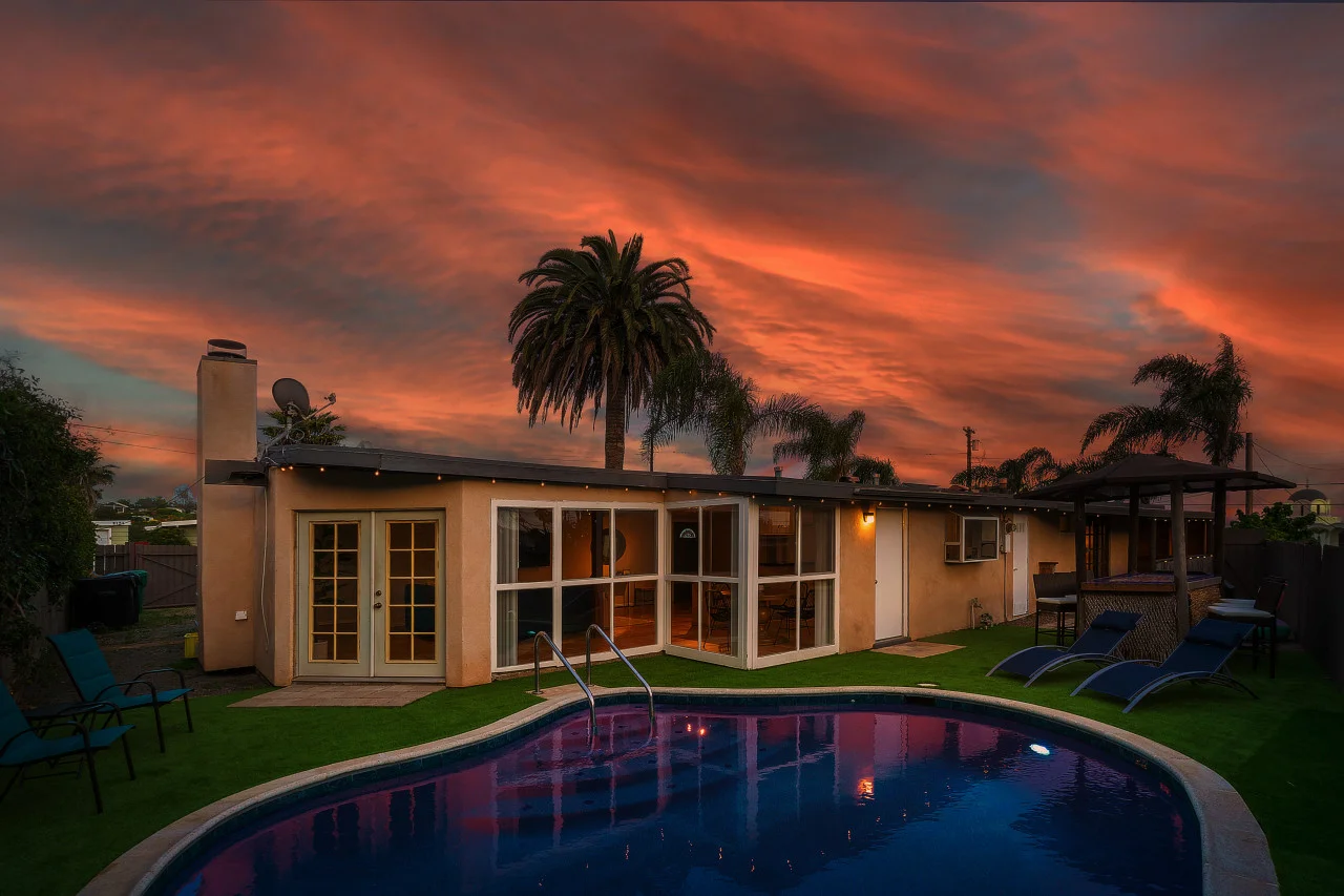 Modern co-hosting property in Mission Beach, CA with curved pool at sunset, featuring mid-century architecture and tropical