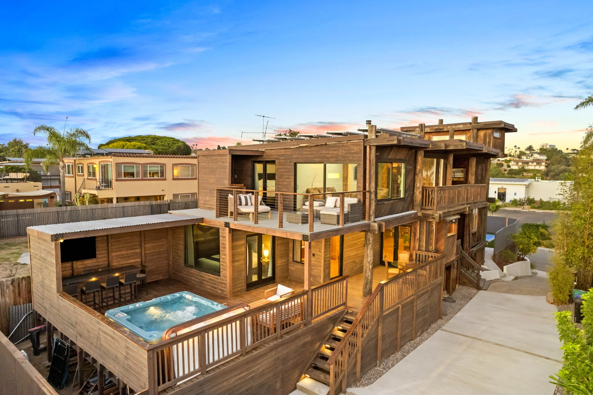 Contemporary San Diego property with wooden deck, hot tub, and outdoor entertaining spaces at sunset