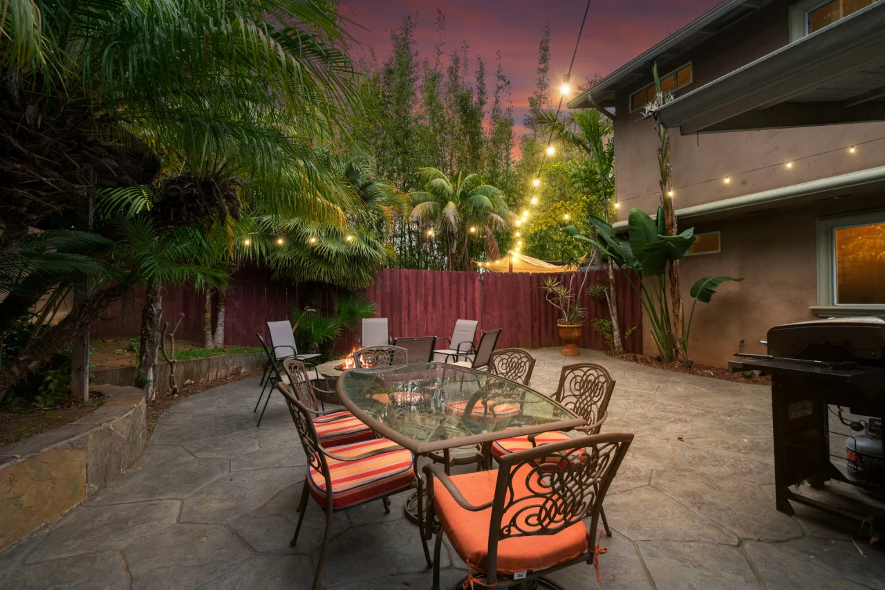 Backyard patio with dining table, fire pit, and tropical landscaping in San Diego