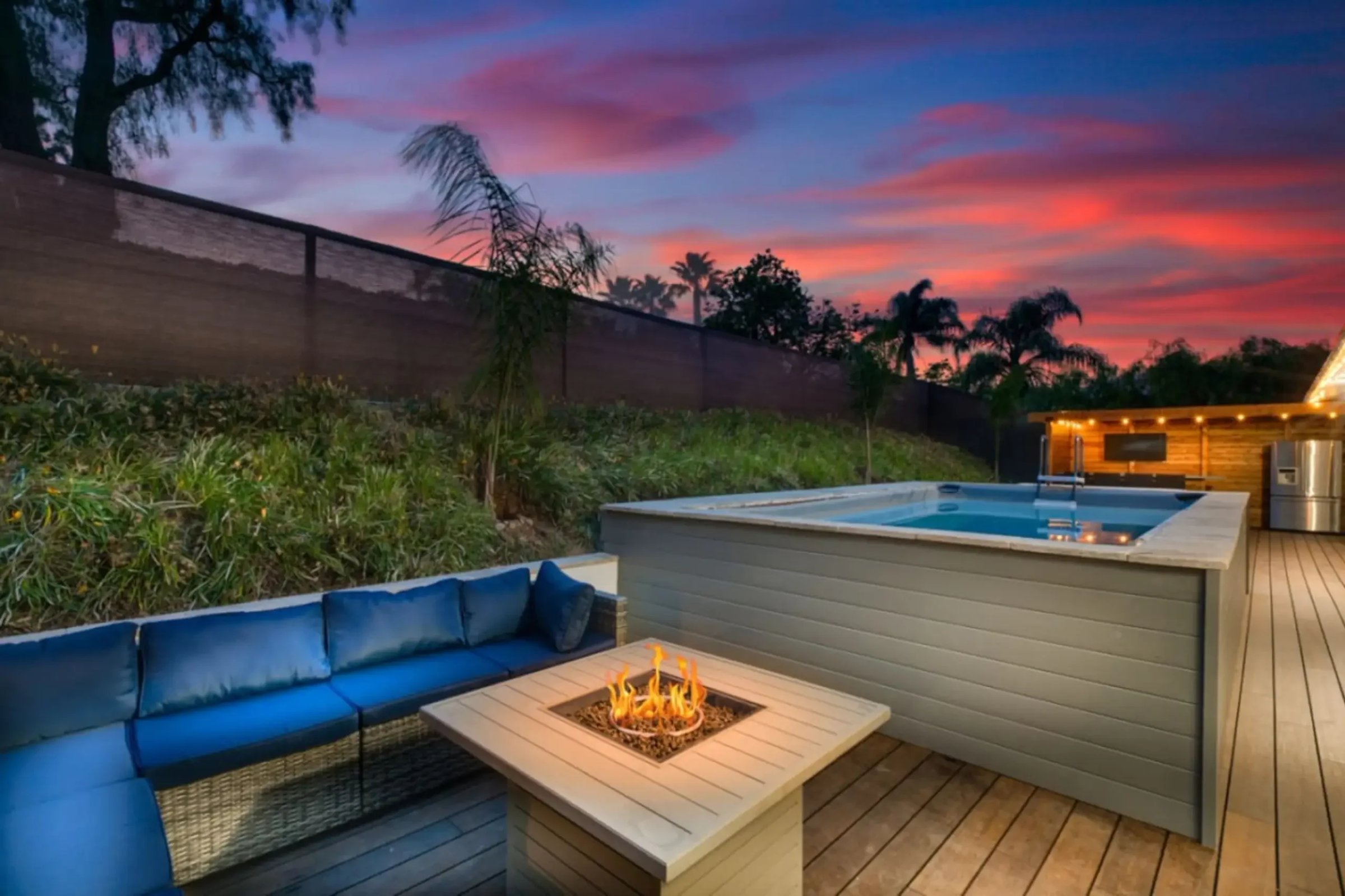 Modern San Diego backyard pool with fire pit seating area and sunset views, representing luxury vacation rental amenities