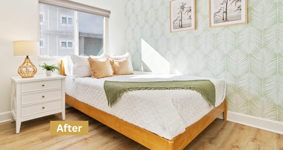 Staged San Diego rental bedroom with natural light, wooden bed, white bedding, sage throw blanket, and botanical artwork for