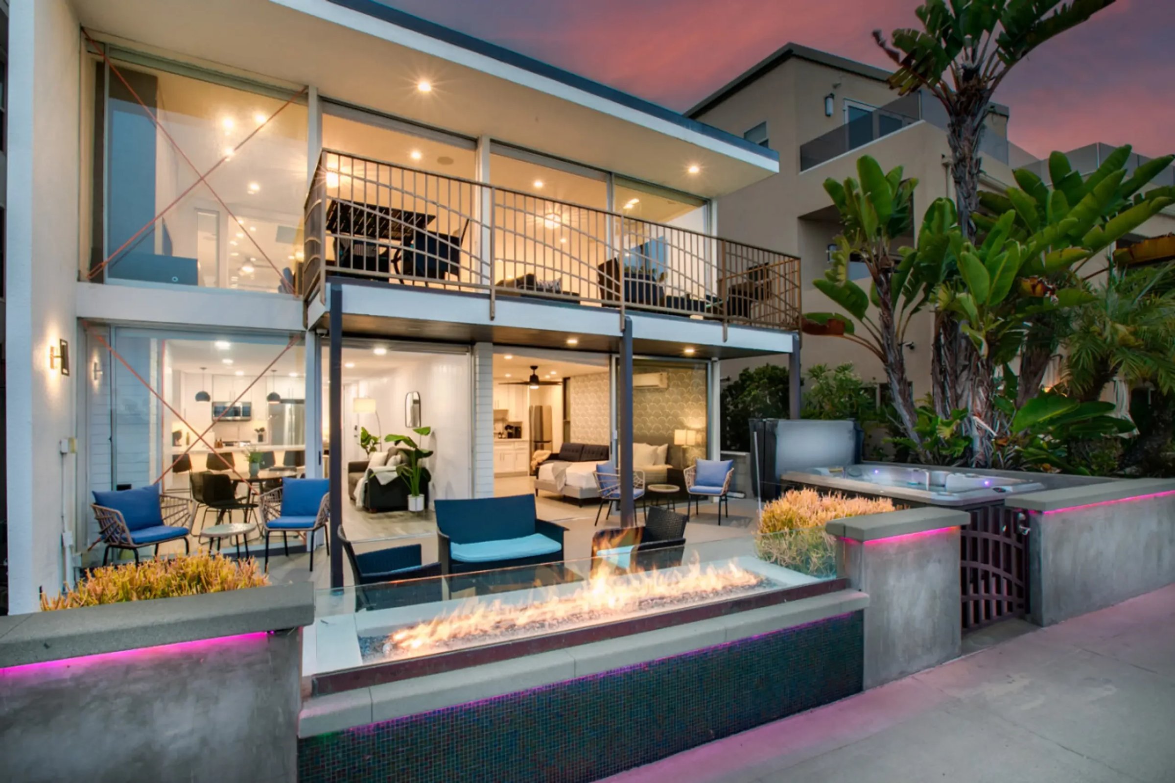 Modern luxury home exterior with glass walls and fireplace in San Diego coastal neighborhood