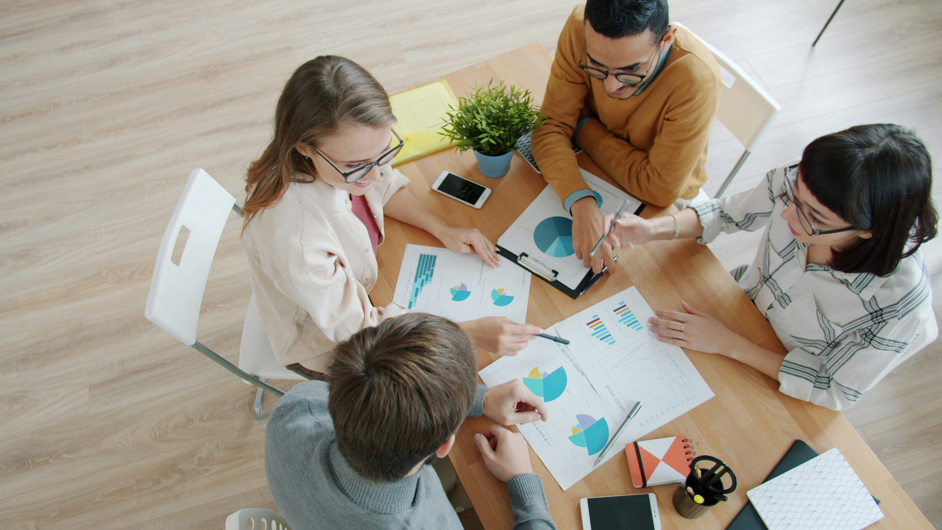 Four people working around a table with charts