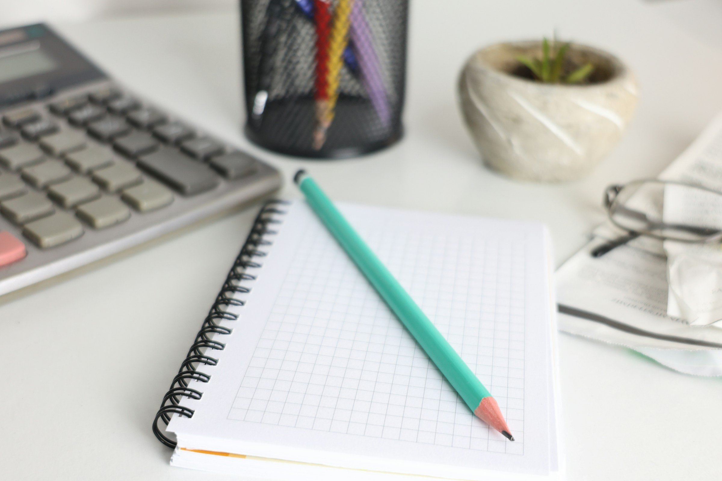 Calculator beside a grid notebook and pencil
