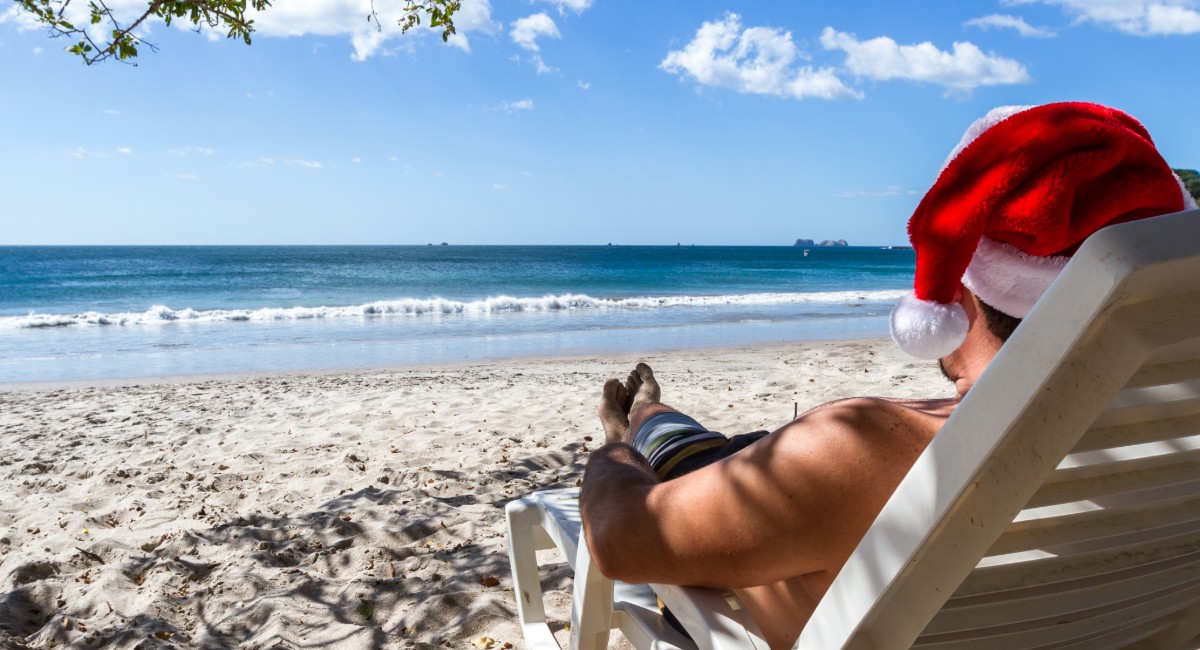 Man relaxing on Maui beach on Christmas Day wearing Santa hat with ocean view