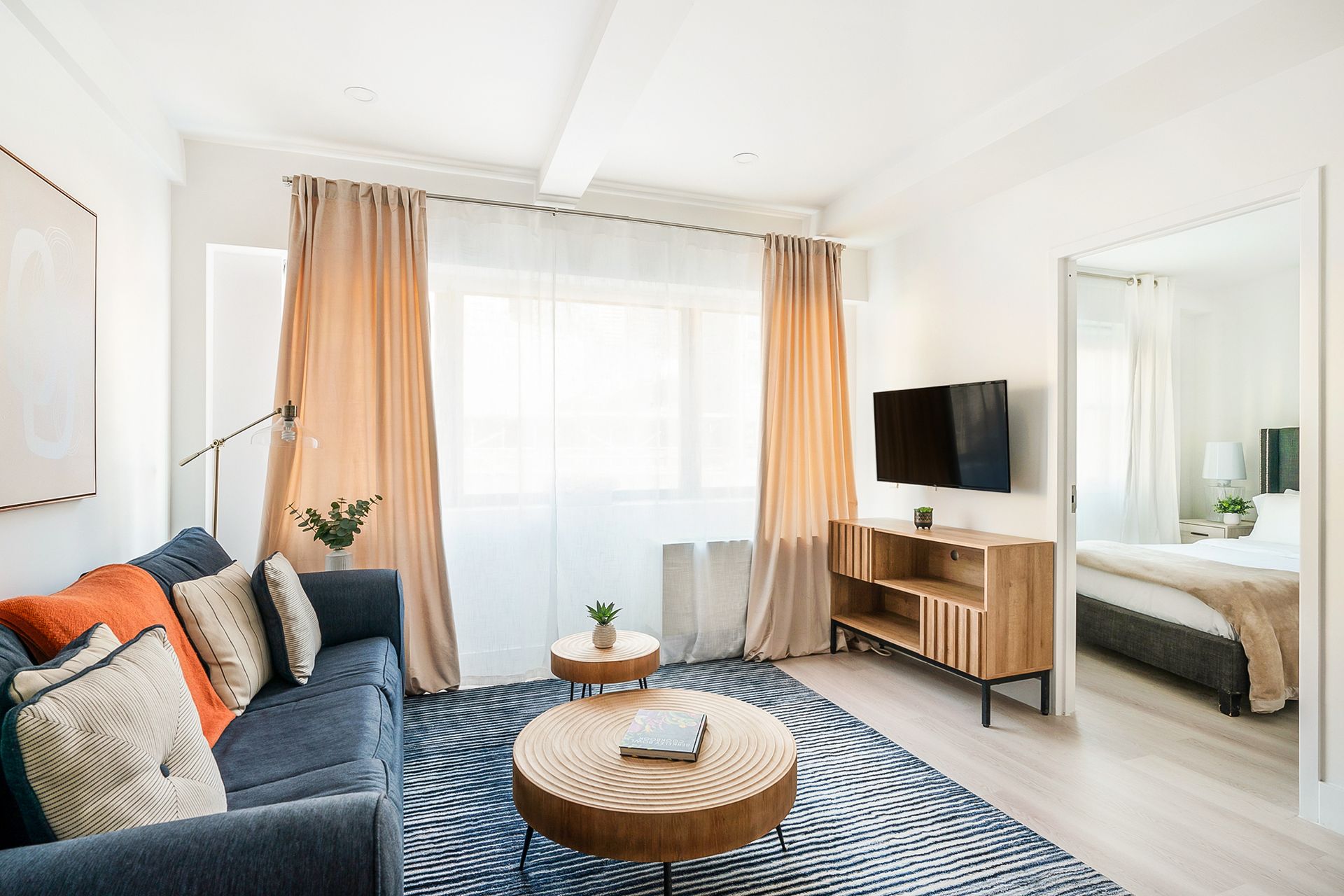Living room with blue sofa, wooden coffee table, and open doorway to bedroom.
