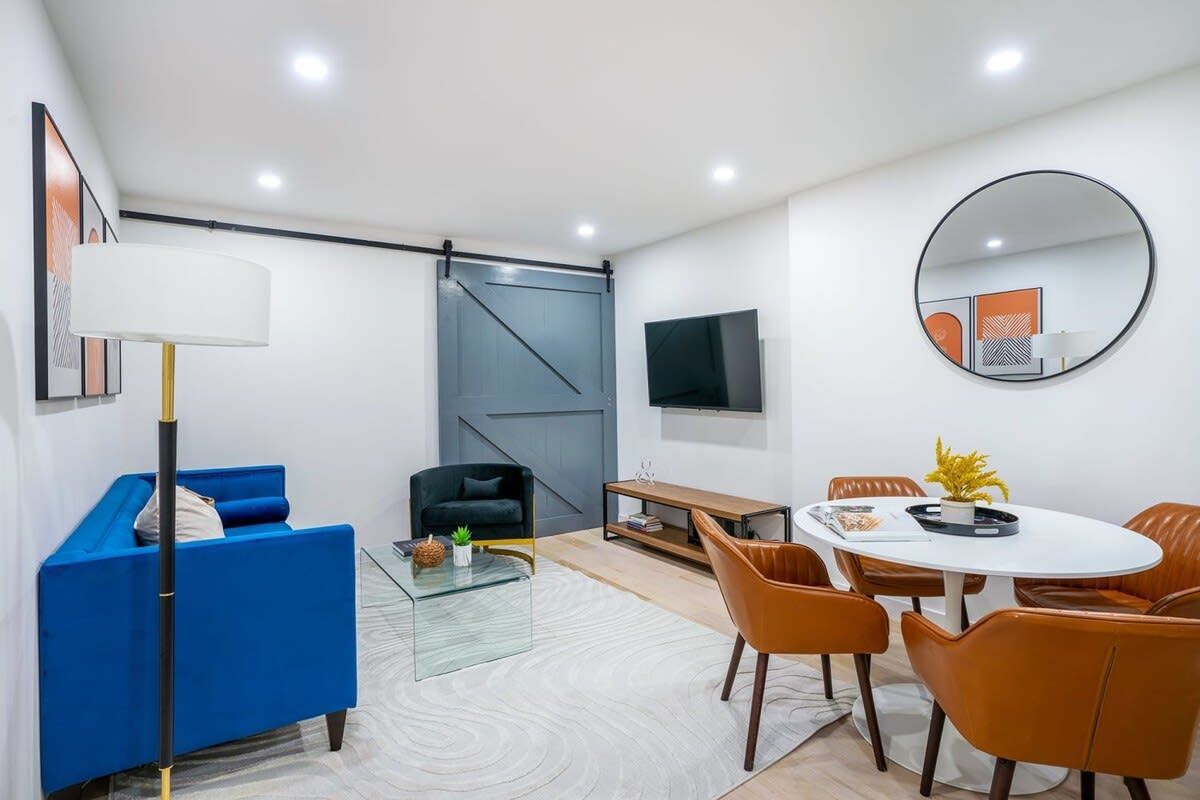 Small, modern living space with blue sofa, round dining table, and accent decor.