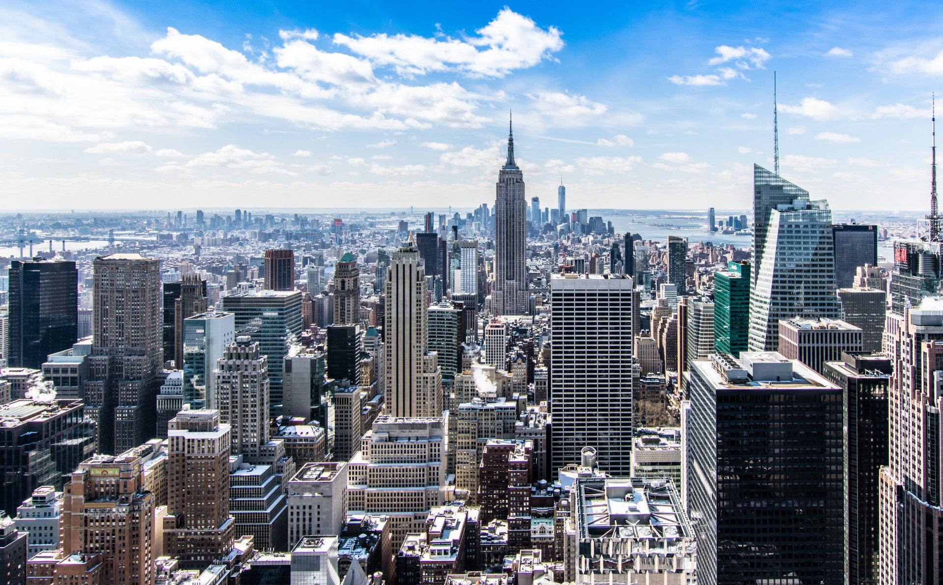 New York City skyline with the Empire State Building under a blue sky.